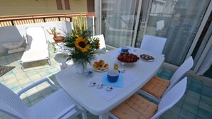 A patio table set with food and drinks, surrounded by white chairs. - Agllipoli Penthouse 215 (Gallipoli)