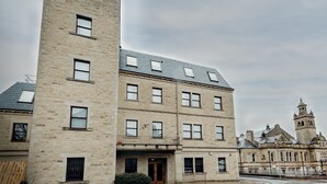Un edificio de varios pisos con fachada de piedra, numerosas ventanas y una torre campanario.