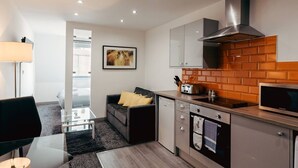 Una cocina moderna con microondas, tostadora y horno. Hay un sofá con cojines y una mesa de vidrio.