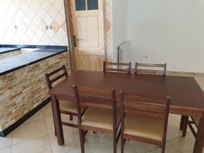 Ein Essbereich mit Holztisch und -stühlen, einer Steinwand und einer Tür.