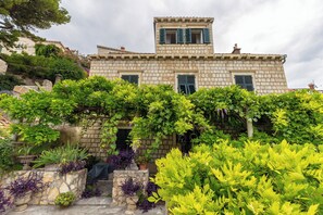 A stone building with a balcony and a garden in front. - Studio Amy - Studio Apartment, Sleeps 2 (Dubrovnik)