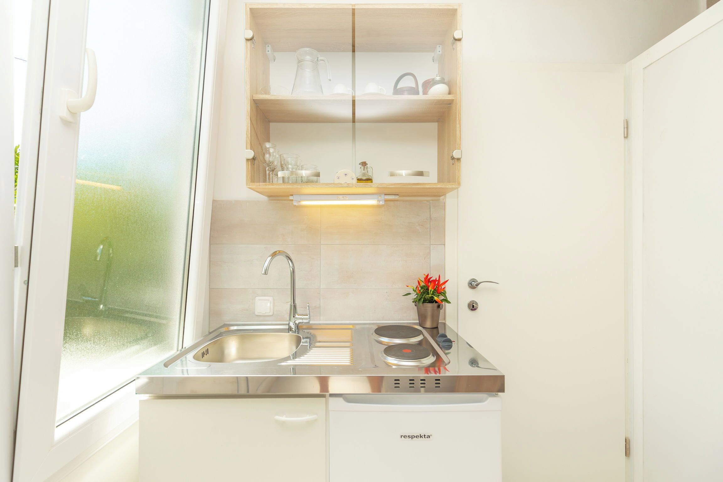 A modern kitchen with a stainless steel sink, a built-in oven, and a double door cabinet.