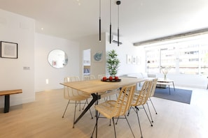 A modern dining area with a wooden table, wicker chairs, and a small potted plant. - Nogalera Terrace III - Adults Only (Torremolinos)