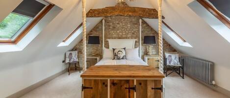 A bedroom with a sloped ceiling, a wooden bed frame, a stone wall, and a skylight.