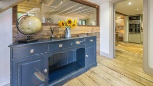 A dark blue wooden console table with a globe and a vase of sunflowers. - Hideaway Barn (4), Thornham, Norfolk (Thornham)