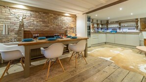 A rustic kitchen with a brick wall, wooden floor, and a cowhide rug. - Hideaway Barn (4), Thornham, Norfolk (Thornham)