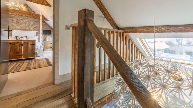 A wooden staircase with a view of a room featuring a stone wall and a bed. - Hideaway Barn (4), Thornham, Norfolk (Thornham)