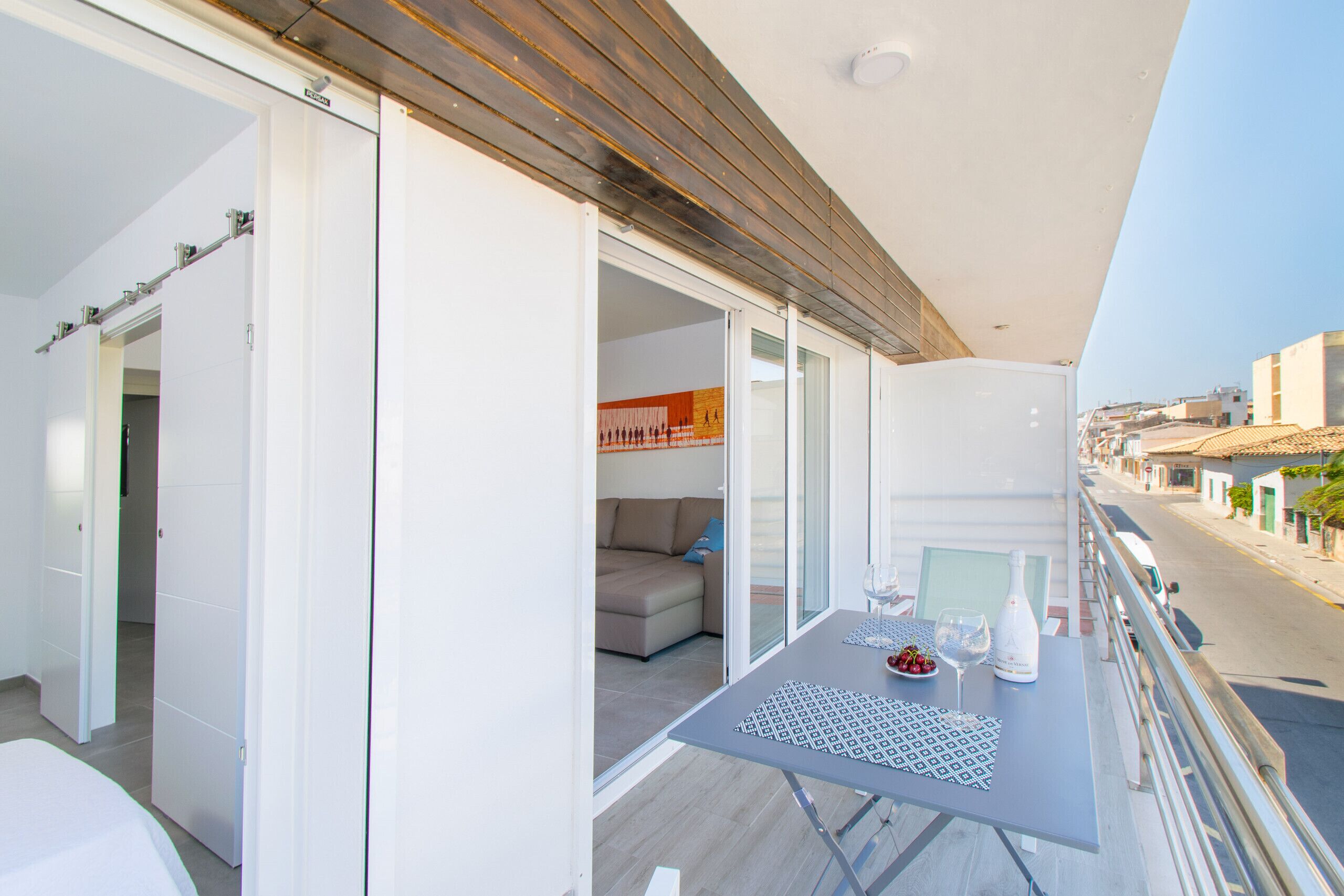 A balcony with a table set for dining, a sofa, and a view of the street.