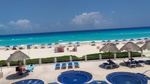 Ein Strandhotel mit mehreren Swimmingpools, Strandliegen und Sonnenschirmen.