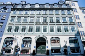 A building with multiple windows, a central entrance, and storefronts on the ground floor.