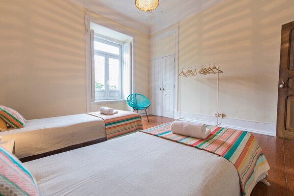 Una habitación con dos camas, una ventana, una silla y un armario.