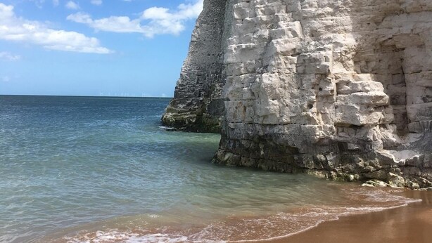 Un paysage côtier avec de hautes falaises blanches et une eau d’un bleu limpide.