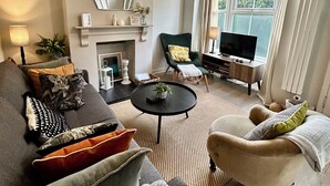 Un salon doté d’une cheminée, d’un téléviseur et d’un coin salon confortable avec un canapé et des fauteuils.