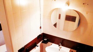 A bathroom with a white sink, a mirror, a towel rack, and a shower area. - My House of Milan 19 (Milano)
