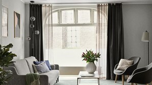 Ein modernes Wohnzimmer mit einem grauen Sofa, einem Couchtisch und zwei Sesseln.