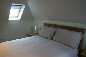 Una camera da letto con un lucernario, una testiera in legno e un comodino con una lampada.