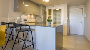 A modern kitchen with a central island, bar stools, a microwave, and a potted plant. - Las Arenas - Haraganes Beach HLHA215P214 (Isla Canela)