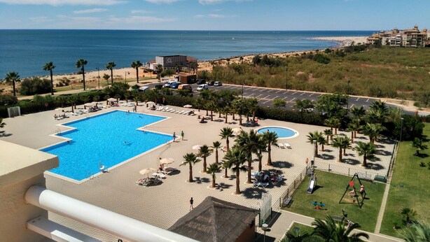 A resort with a large swimming pool, palm trees, and a view of the beach and ocean. - Las Arenas - Haraganes Beach HLHA215P214 (Isla Canela)