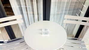 Ein runder Tisch mit einer transparenten Glasdekoration, umgeben von weißen Stühlen mit Metallgestellen.