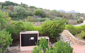 Guest house nestled among lush greenery with a clear view of distant mountains.