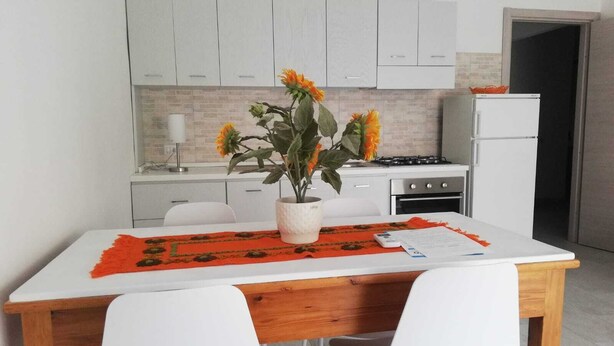 Een moderne keuken met witte kasten, een houten tafel en twee witte stoelen.
