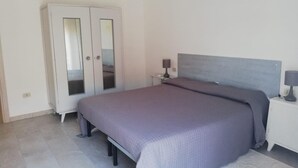 Een slaapkamer met een bed, een kledingkast en een nachtkastje.
