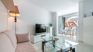 Ein modernes Wohnzimmer mit Glastisch, Flachbildfernseher, Sofa und Lampe.