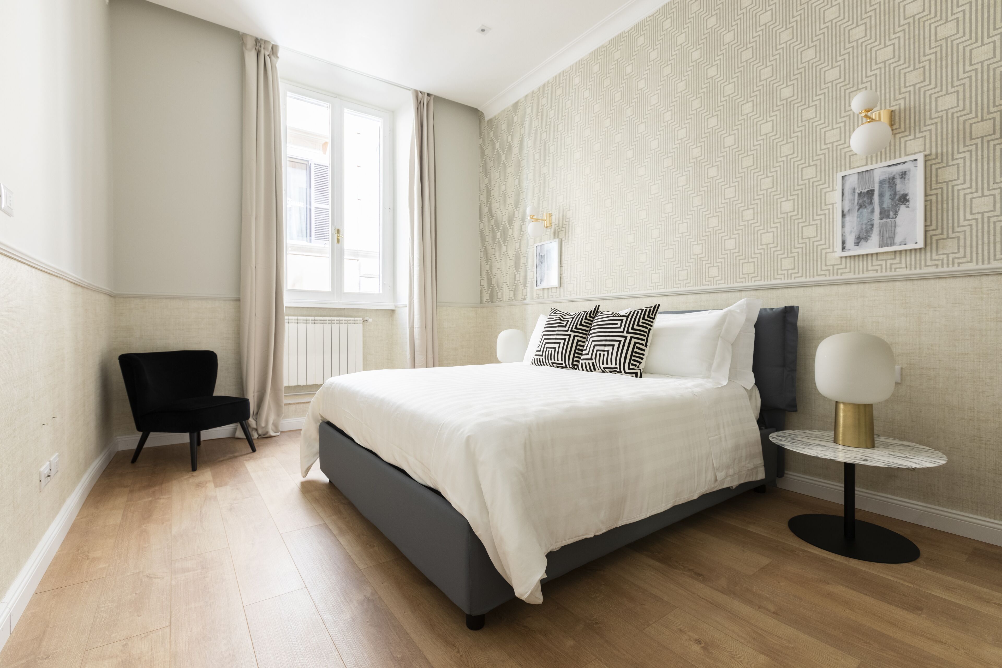 A modern bedroom with a large bed, a small round table, and a chair.