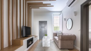Ein modernes Wohnzimmer mit Flachbildfernseher, einem Marmortisch, einem beigefarbenen Sofa und einer Holztreppe.