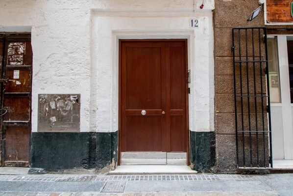 A building with a brown door, white and green painted walls, and a black metal gate.