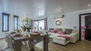 A modern living room with a dining area, featuring a sofa set, a dining table with chairs, a potted plant, and a wall clock. - ★Luxury 1 Bedroom Apartment, 3 min Walk to the Beach, Albufeira (Albufeira)