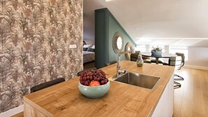 A modern kitchen with a wooden island, a bowl of fruit, and a dining area with a table and chairs.