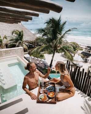 A couple dining by a pool with a view of the beach and palm trees. - Hotel Ma'xanab (Tulum)