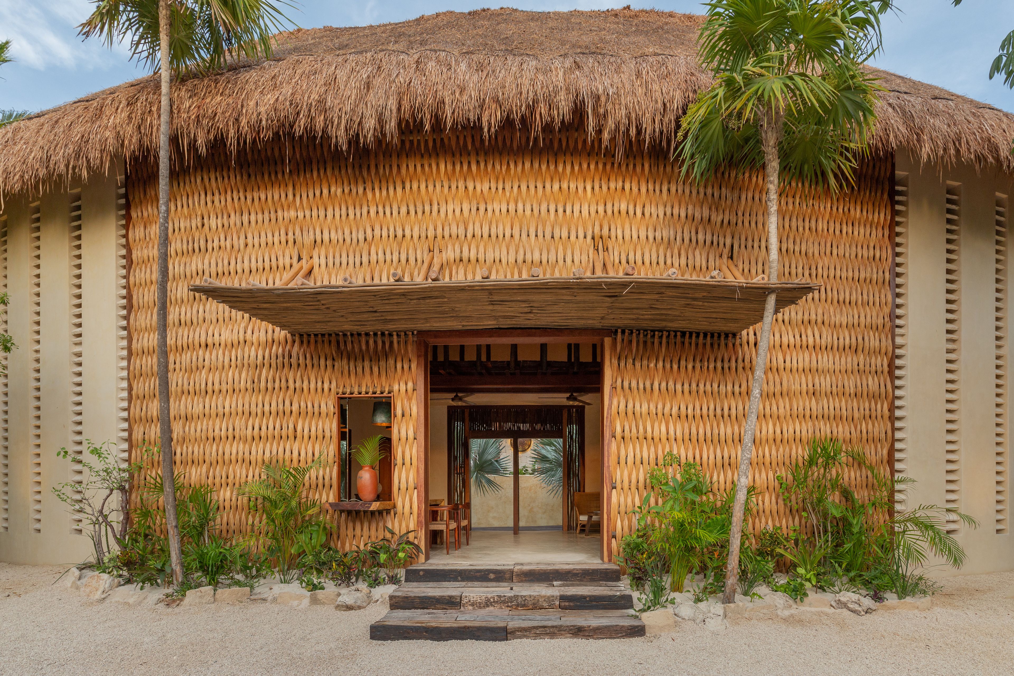 A thatched-roof building with a wooden entrance and steps leading up to it.