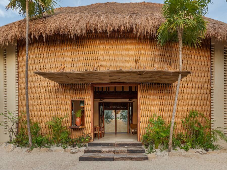 A thatched-roof building with a wooden entrance and steps leading up to it.