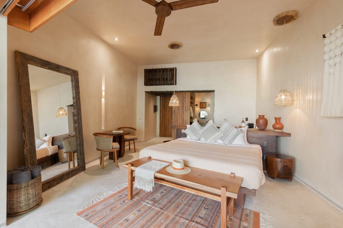 Un dormitorio espacioso con una cama grande, un banco de madera, un escritorio y una silla.