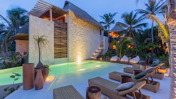Relax by the pool surrounded by lush greenery and palm trees in a serene outdoor setting.