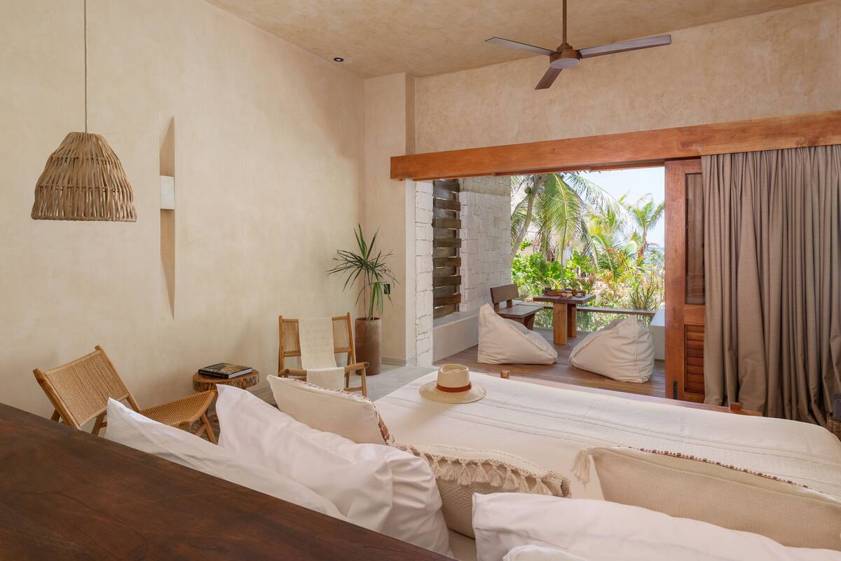 Un dormitorio con cama, una mesa de madera, una lámpara colgante y vistas al exterior.