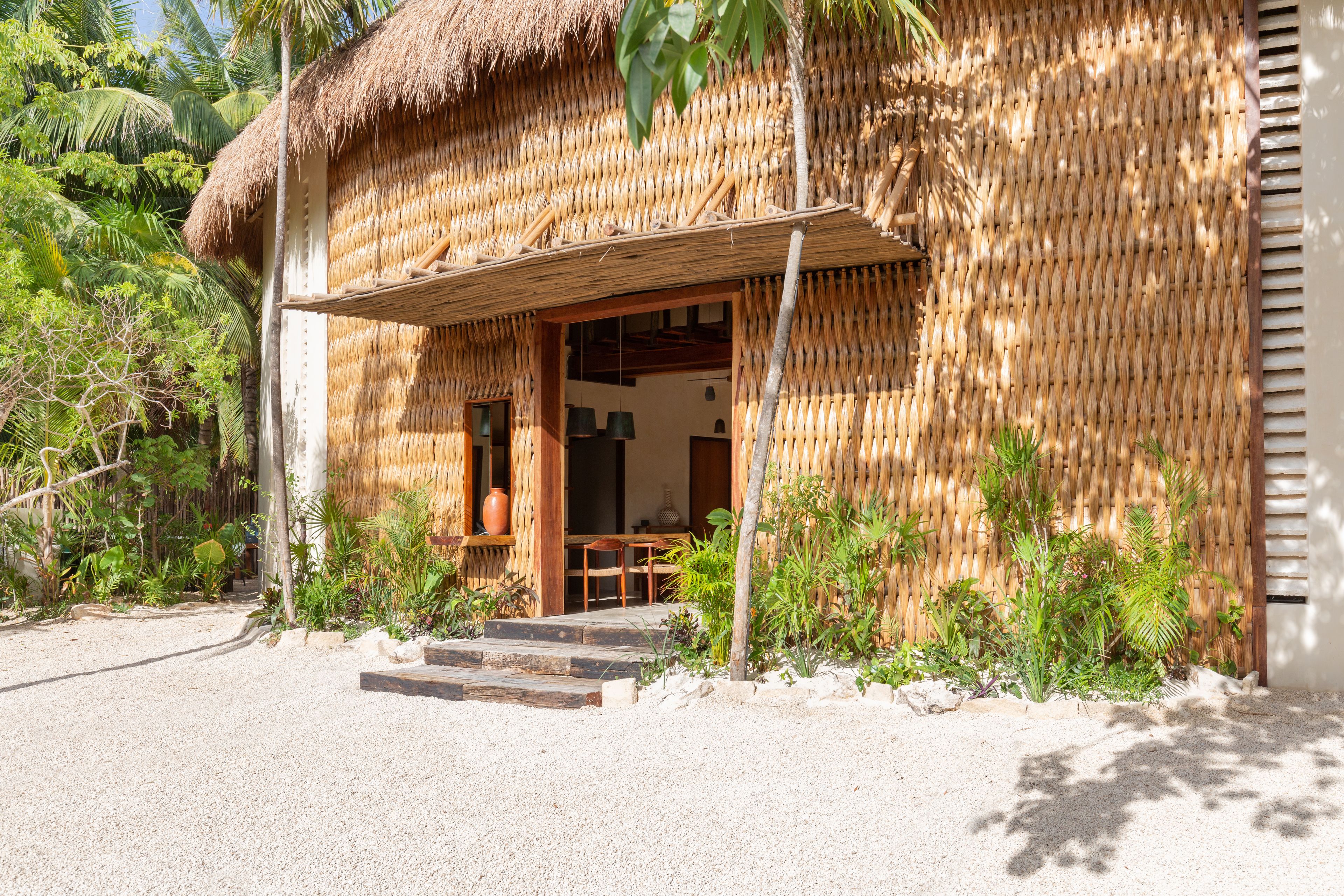 A thatched-roof building with a wooden porch and steps leading to the entrance.