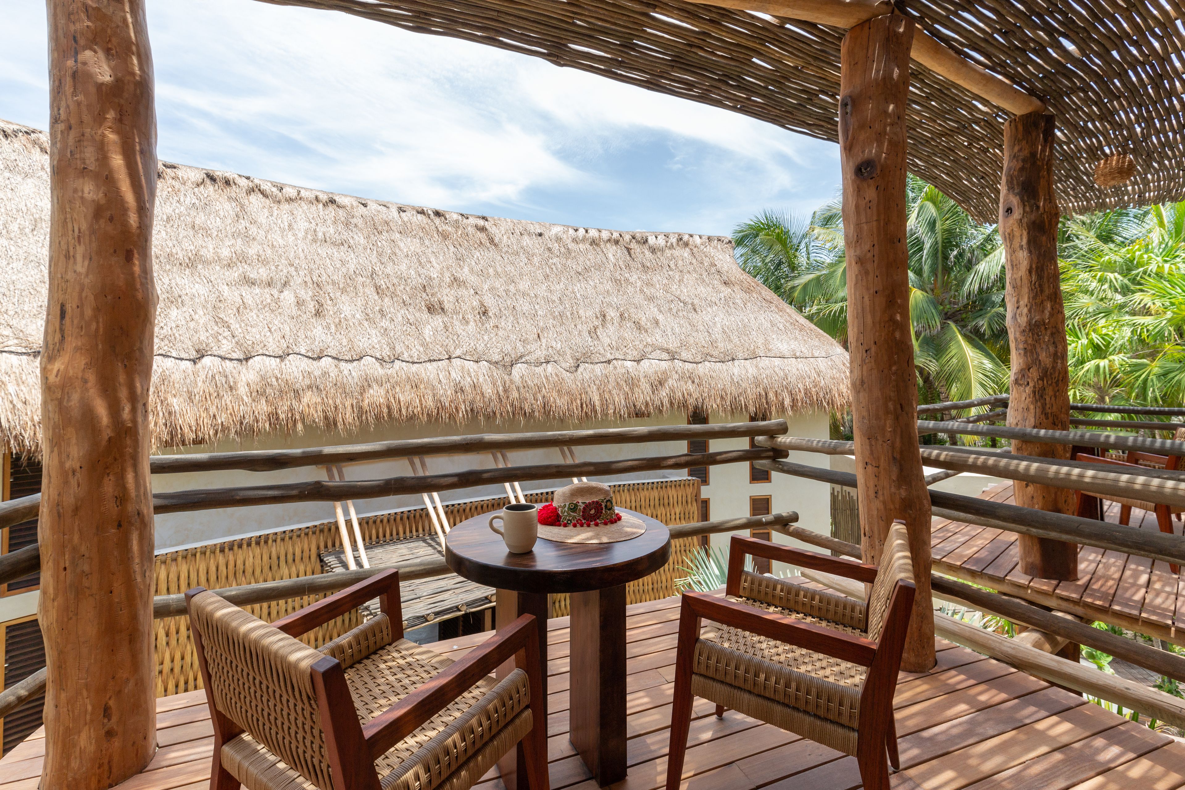 A wooden deck with wicker furniture and a thatched roof structure.
