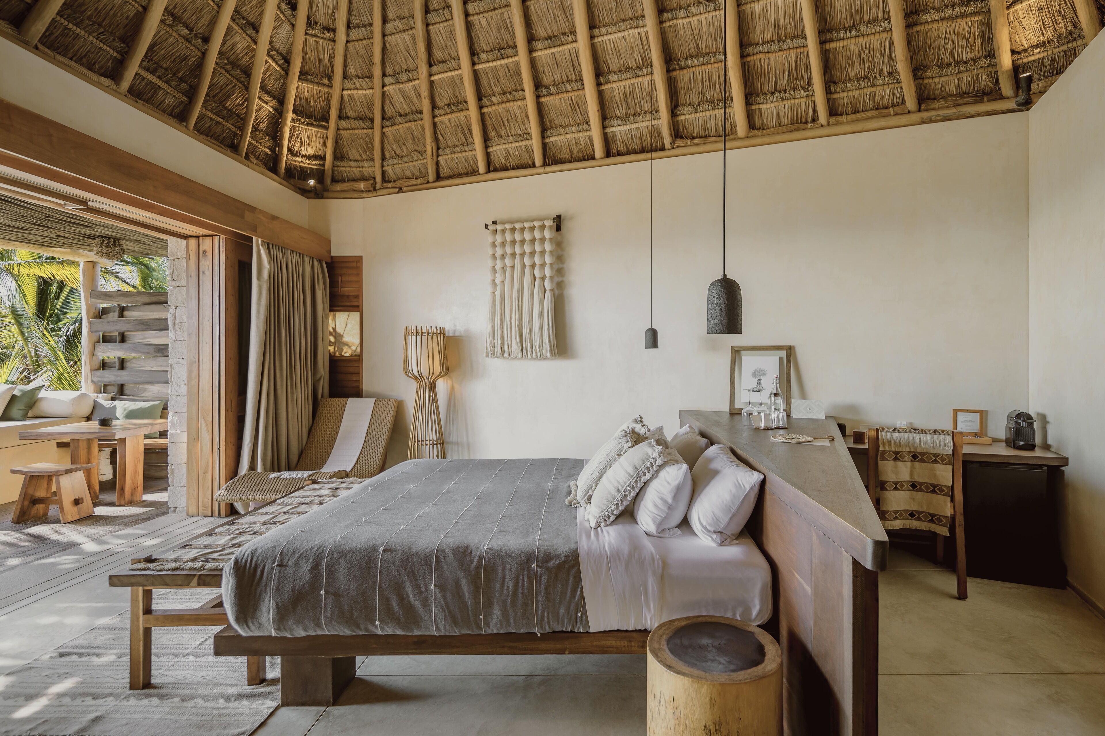 Un dormitorio espacioso con una cama grande, muebles de madera y un techo de paja.