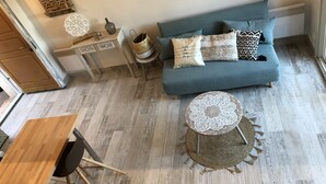 A cozy living room with a blue sofa, a round coffee table, and a wooden dining table.