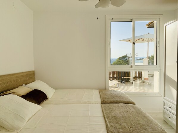 Un dormitorio con una cama grande, una ventana con vistas a muebles de exterior y un armario blanco.