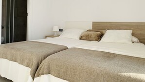 A double bed with a wooden headboard, two bedside tables with lamps, and a bathroom with a glass shower enclosure. - SEA VIEW APT, BEACHFRONT, PARKING, AA/CC, WIFI, LARGE TERRACE (Salou)
