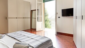 Un dormitori amb llit, armari, televisió i un balcó amb vistes.