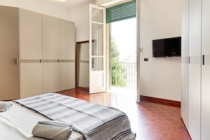 Une chambre à coucher comprenant un lit, une armoire, une télévision et un balcon avec vue.