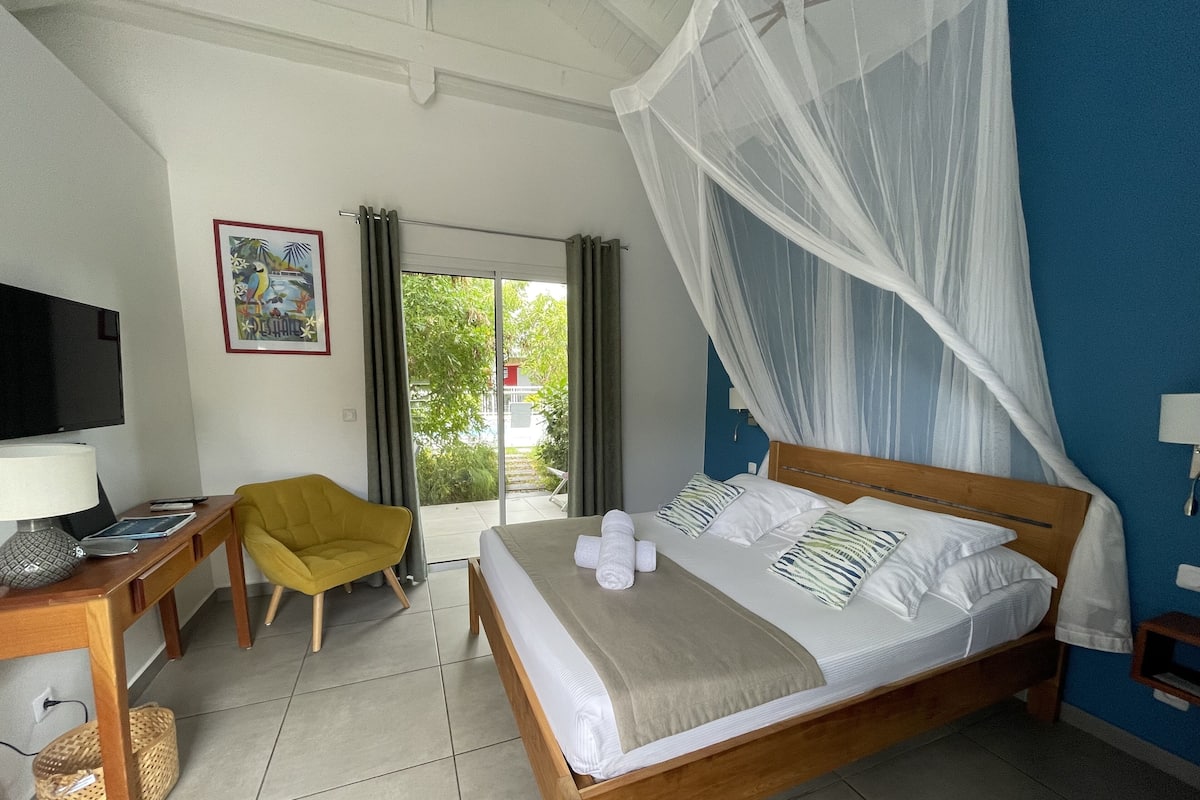 A hotel room with a bed, a TV, a desk, a chair, and a window with curtains.