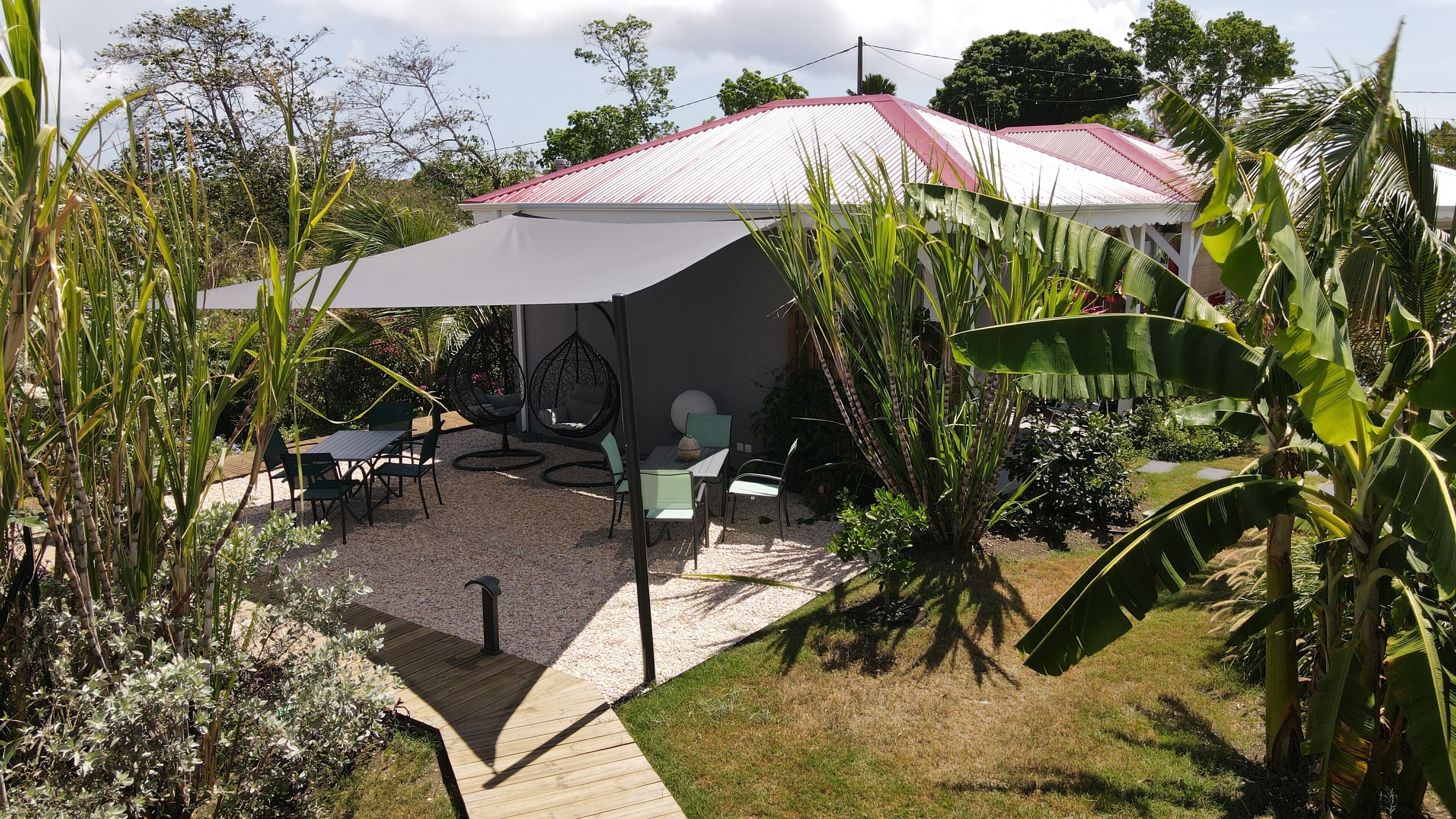 Un patio con mesa y sillas, rodeado de plantas y un paraguas grande.