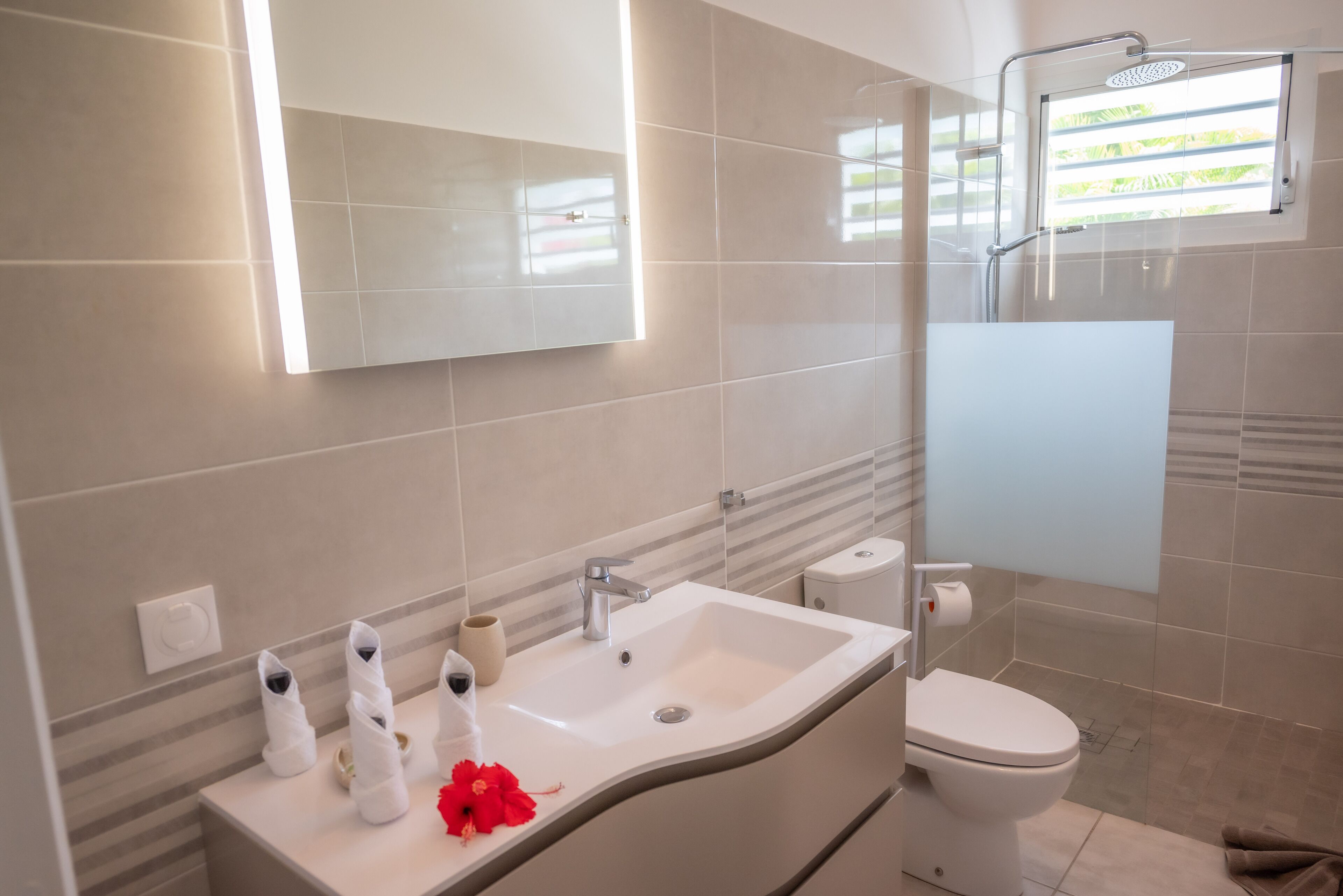 Een moderne badkamer met een wit wastafelmeubel, spiegel en toilet.
