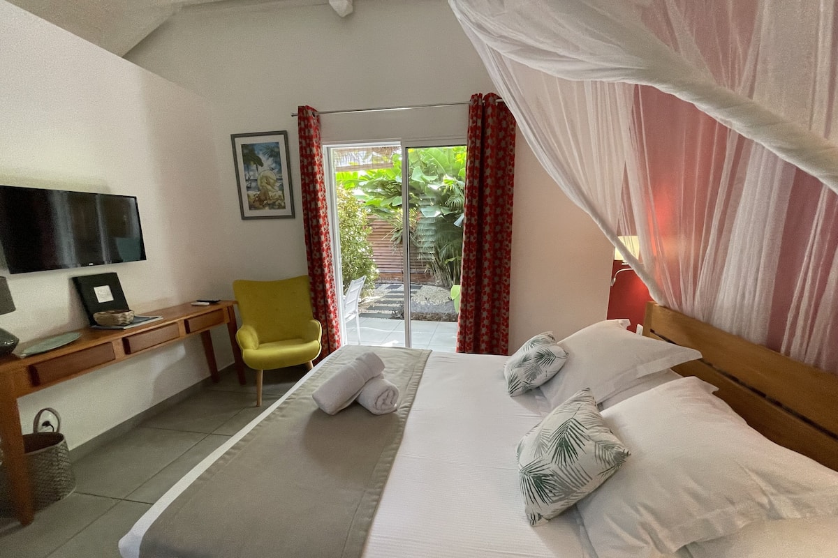 A hotel room with a bed, a desk, a chair, a TV, and a view of the outdoors.